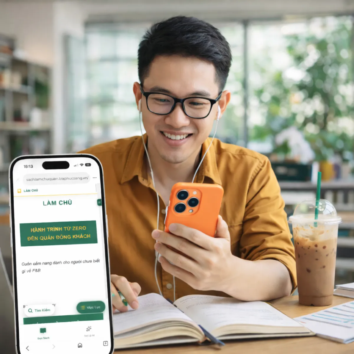 Người đọc sách điện tử Làm Chủ Quán trên điện thoại tại quán cà phê, bên cạnh sổ ghi chép